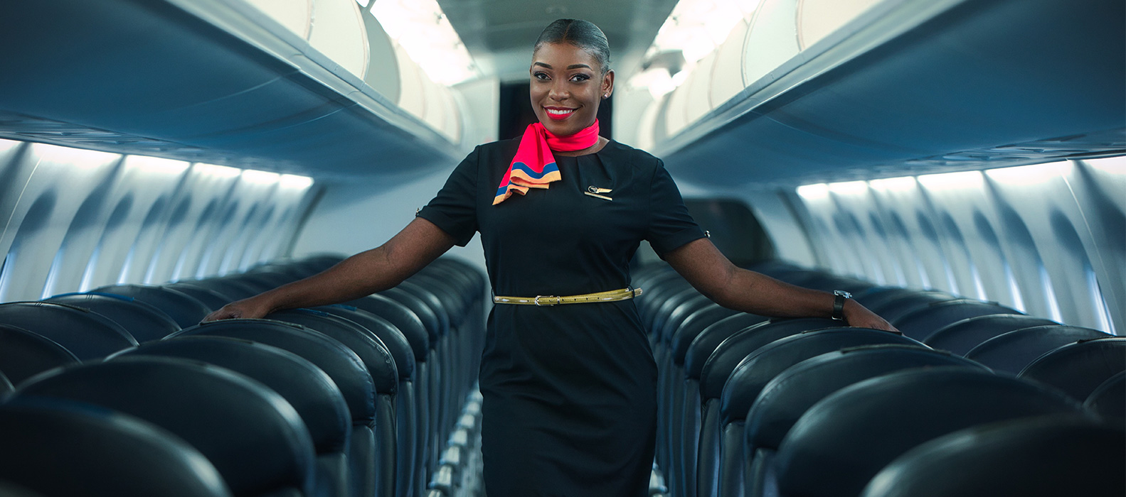 Une hôtesse de Congo Airways sourit dans l'allée de la cabine